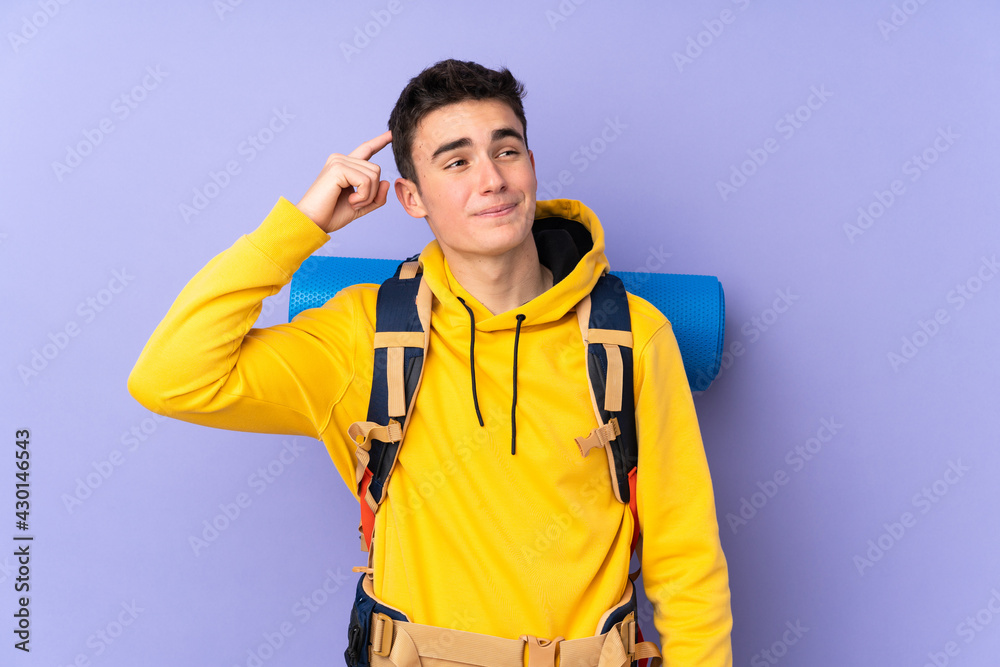 Teenager caucasian mountaineer man with a big backpack isolated on purple background having doubts and with confuse face expression Teenager caucasian mountaineer man with a big backpack isolated on purple background having doubts and with confuse face expression