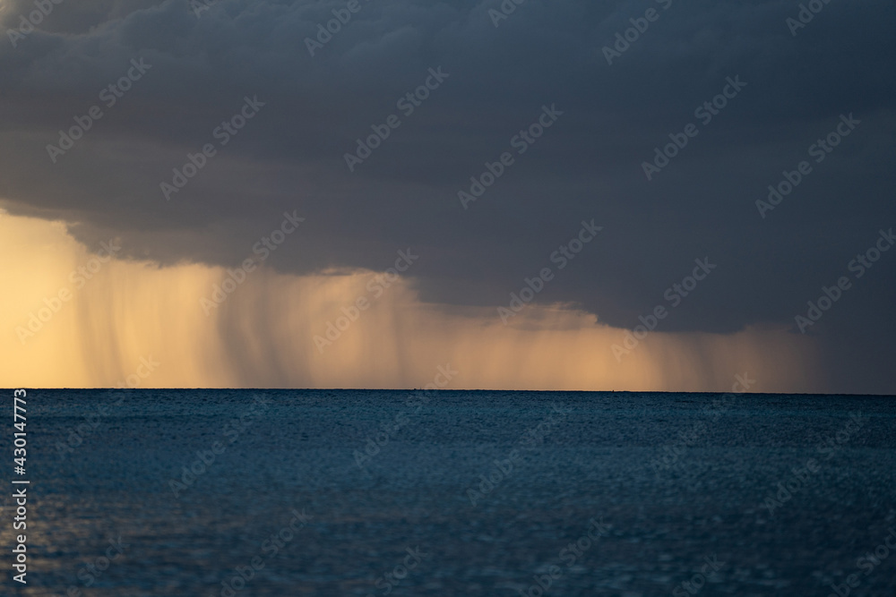 Heavy rain, stormy clouds and storm over seascape during dramatic sunset 