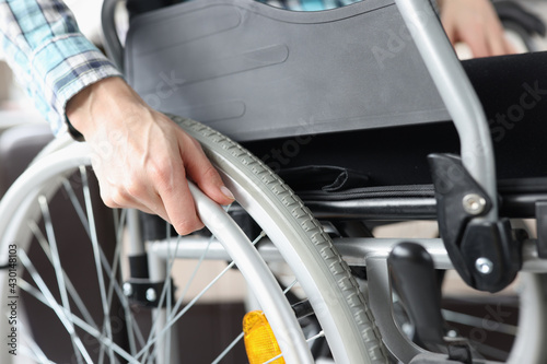 Disabled woman sitting in wheelchair and holding on to wheel closeup