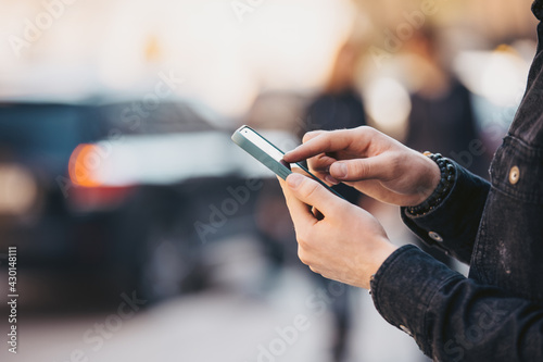 Closeup male hand holding smartphone in a city