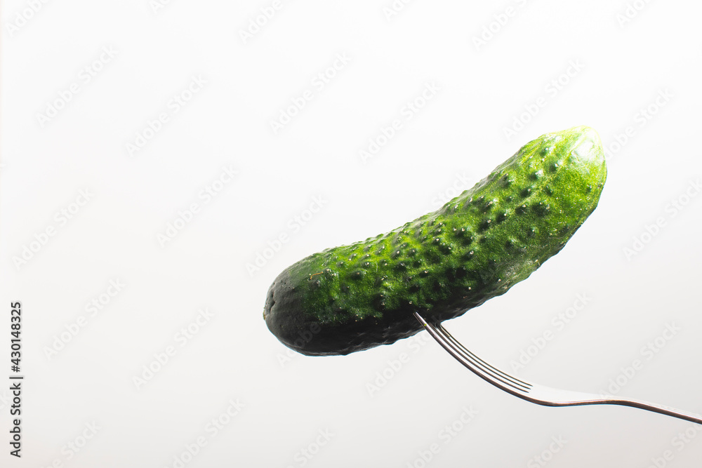 green cucumber on a fork on a white background green cucumber on a fork on a white background