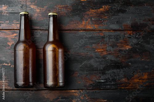 Fotografia Fresh beer in glass bottles, on old dark  wooden table , top view flat lay, with