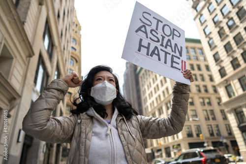 Asian woman holding Stop Asian Hate sign protesting on a street in New York City