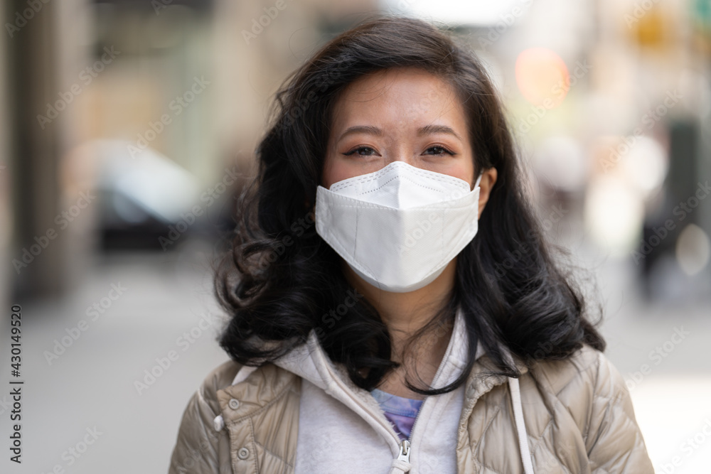 Asian woman wearing a mask smile happy face portrait on a city street Asian woman wearing a mask smile happy face portrait on a city street