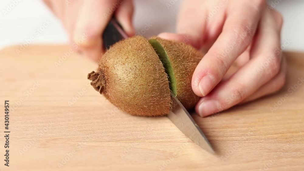 Woman cuts ripe kiwi fruit, close-up