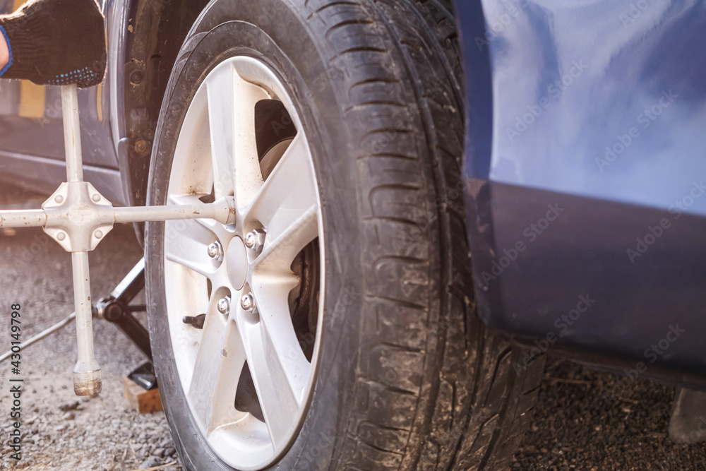 Car wheel replacement. Self-service tire fitting concept. Using a wheel wrench to twist the wheel nuts.