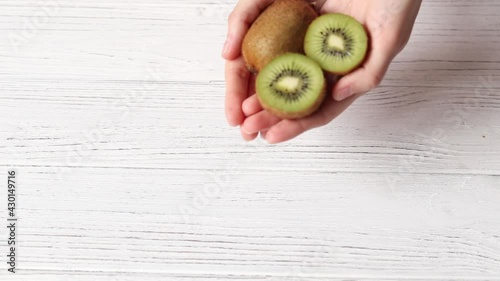 Female hands hold ripe kiwi