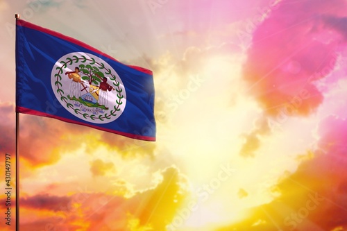 Fluttering Belize flag in top left corner mockup with the space for your text on beautiful colorful sunset or sunrise background.