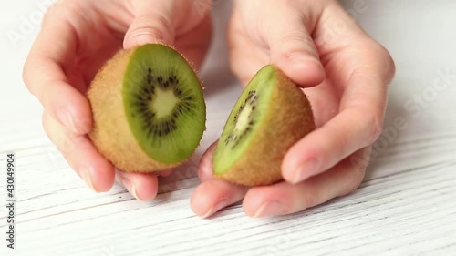 Female hands hold ripe kiwi