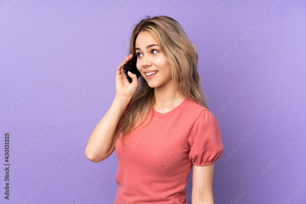 Teenager Russian girl isolated on purple background keeping a conversation with the mobile phone with someone Teenager Russian girl isolated on purple background keeping a conversation with the mobile phone with someone