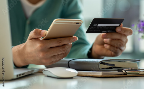 Close up woman hand using credit card and smartphone laptop for buying online shopping