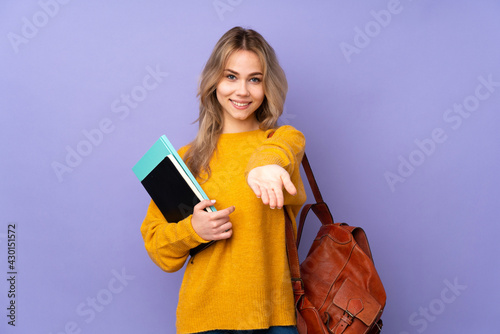 Teenager Russian student girl isolated on purple background holding copyspace imaginary on the palm to insert an ad