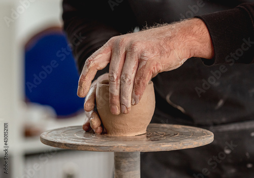 Man working on pottery wheel with clay