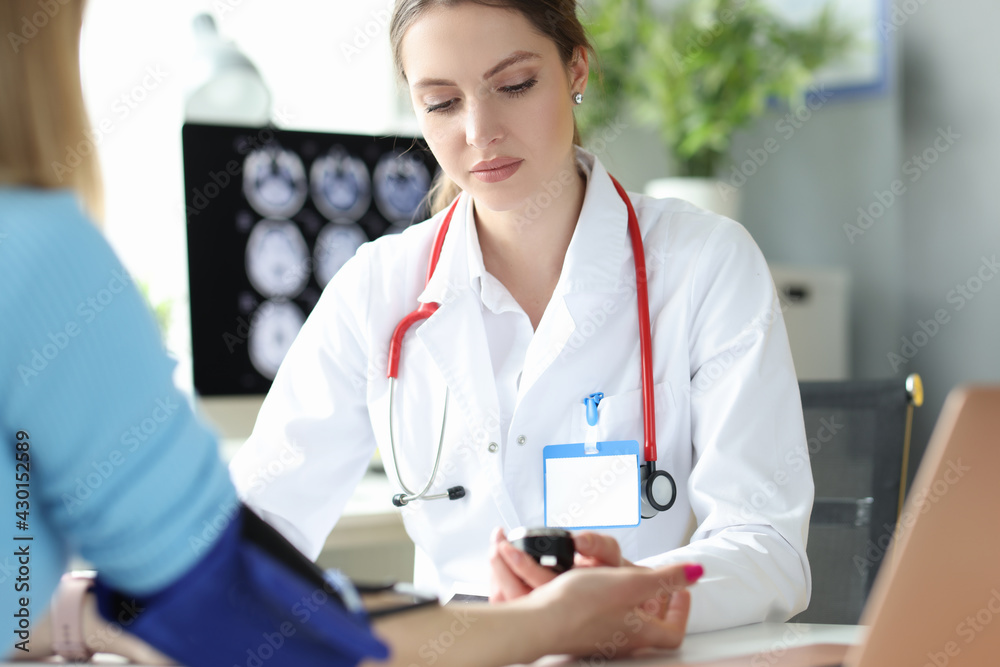 Woman cardiologist measuring blood pressure to patient in clinic Woman cardiologist measuring blood pressure to patient in clinic
