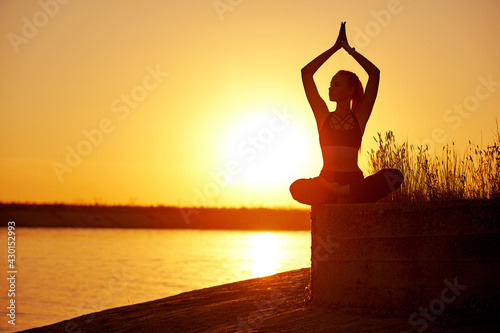Silhouette woman with yoga posture on the beach pier at sunset or sunrise