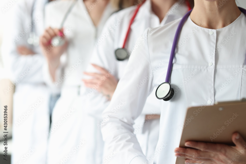 Group of doctors with stethoscope around their neck stands in clinic closeup
