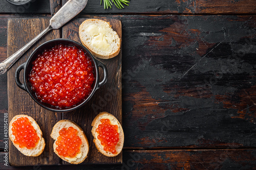 Bruschettes with butter red caviar, on old dark wooden table background, top view flat lay with copy space for text