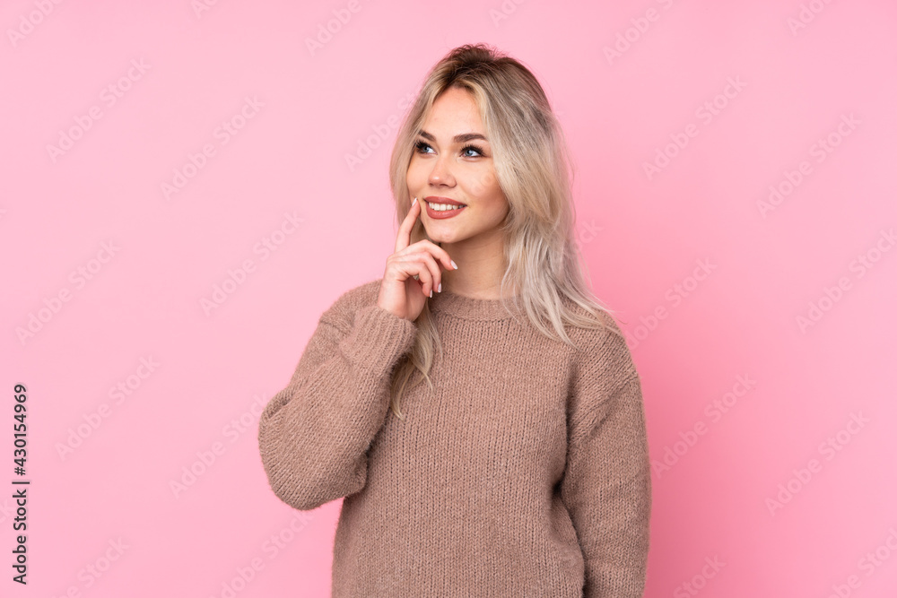Teenager blonde girl wearing a sweater over isolated pink background thinking an idea while looking up Teenager blonde girl wearing a sweater over isolated pink background thinking an idea while looking up