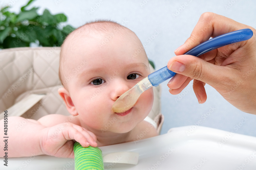 Feeding the baby. Mom feeds the child vegetable puree with a spoon. Happy kid Feeding the baby. Mom feeds the child vegetable puree with a spoon. Happy kid