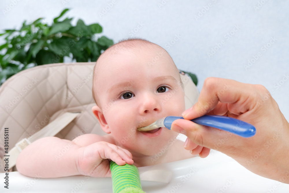Feeding the baby. Mom feeds the child vegetable puree with a spoon. Happy kid Feeding the baby. Mom feeds the child vegetable puree with a spoon. Happy kid