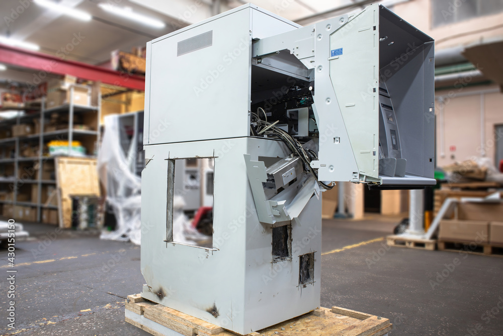 A hacked ATM with a huge hole in the safe and a sawn-off door. Broken gutted ATM from which cash was stolen. A hacked ATM with a huge hole in the safe and a sawn-off door. Broken gutted ATM from which cash was stolen.