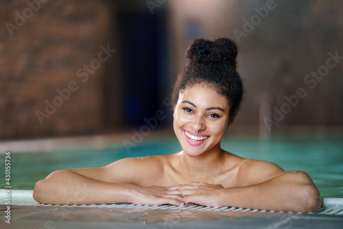 Portrait of young woman in indoor swimming pool  looking at camera.