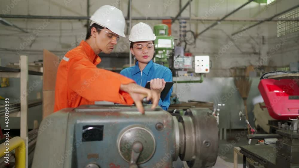 Engineer worker inspect the rolling machine in the factory with colleague. Woman see checklist from tablet. Preventive maintenance in factory. Industrial, technology and innovation concept. 