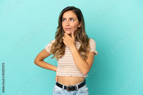 Young woman over isolated blue background thinking an idea while looking up