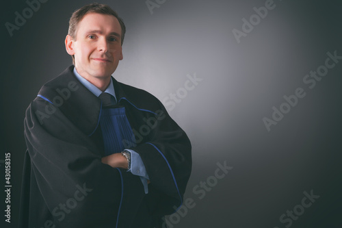 Smiling lawyer in a toga stands with his arms folded photo