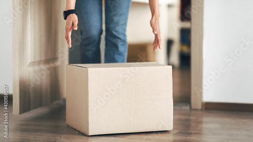 Unrecognizable person picking cardboard box up from the floor © Prostock-studio