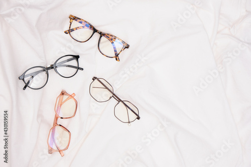 multiple eyes glasses on white crumpled fabric copy space top view