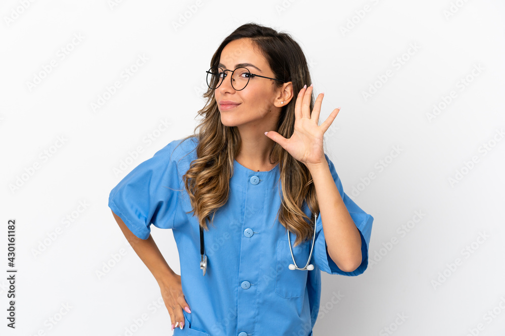 Young surgeon doctor woman over isolated white wall listening to something by putting hand on the ear Young surgeon doctor woman over isolated white wall listening to something by putting hand on the ear