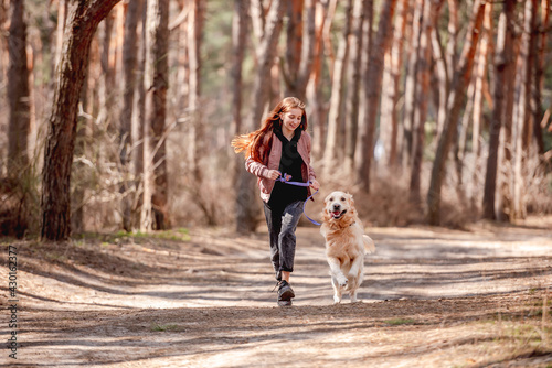 Girl with golden retriever dog in the wood