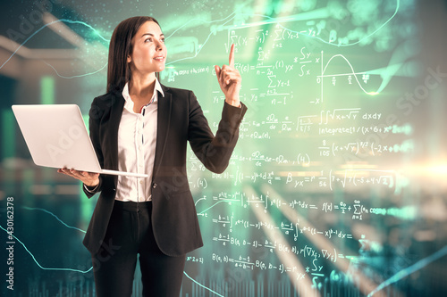 Online education and training concept with young woman with laptop on virtual wall background with mathematical formulas photo