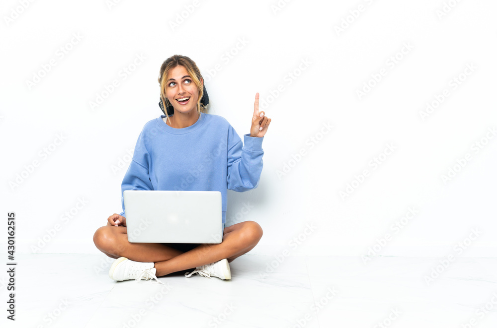 Young blonde Uruguayan girl with the laptop isolated on white background pointing up and surprised Young blonde Uruguayan girl with the laptop isolated on white background pointing up and surprised