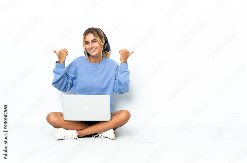 Young blonde Uruguayan girl with the laptop isolated on white background with thumbs up gesture and smiling Young blonde Uruguayan girl with the laptop isolated on white background with thumbs up gesture and smiling