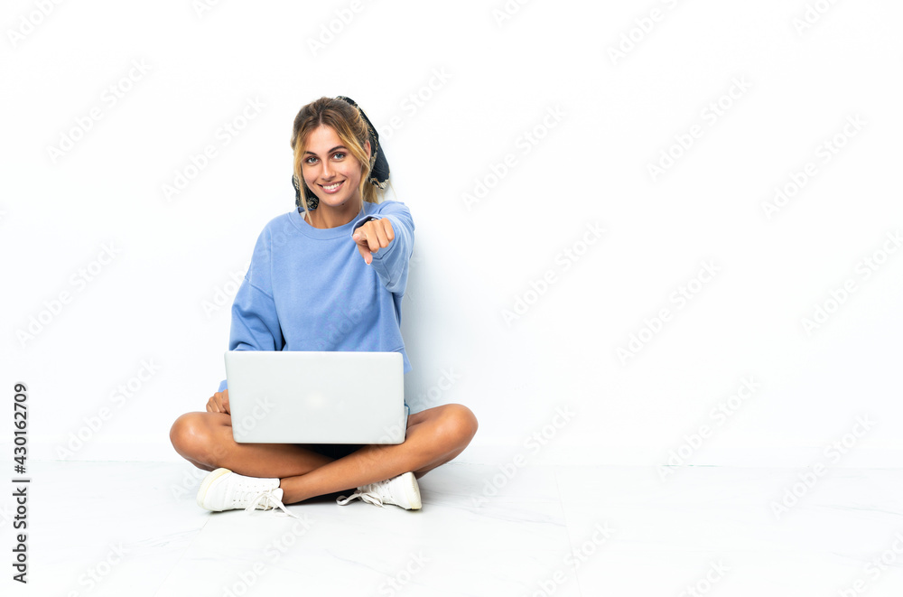 Young blonde Uruguayan girl with the laptop isolated on white background points finger at you with a confident expression Young blonde Uruguayan girl with the laptop isolated on white background points finger at you with a confident expression
