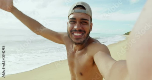 Friendly young Latin American man inviting to come to Brazil, confident and smiling making a gesture with his hand, being positive and friendly. Beach from Brazil. 4K. photo