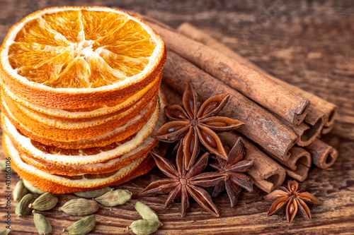 Dry orange slices, anise stars, cinnamon, cardamom and roasted coffee beans on a wooden table. 