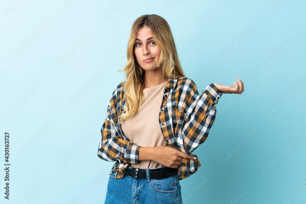 Young blonde Uruguayan isolated on blue background having doubts Young blonde Uruguayan isolated on blue background having doubts