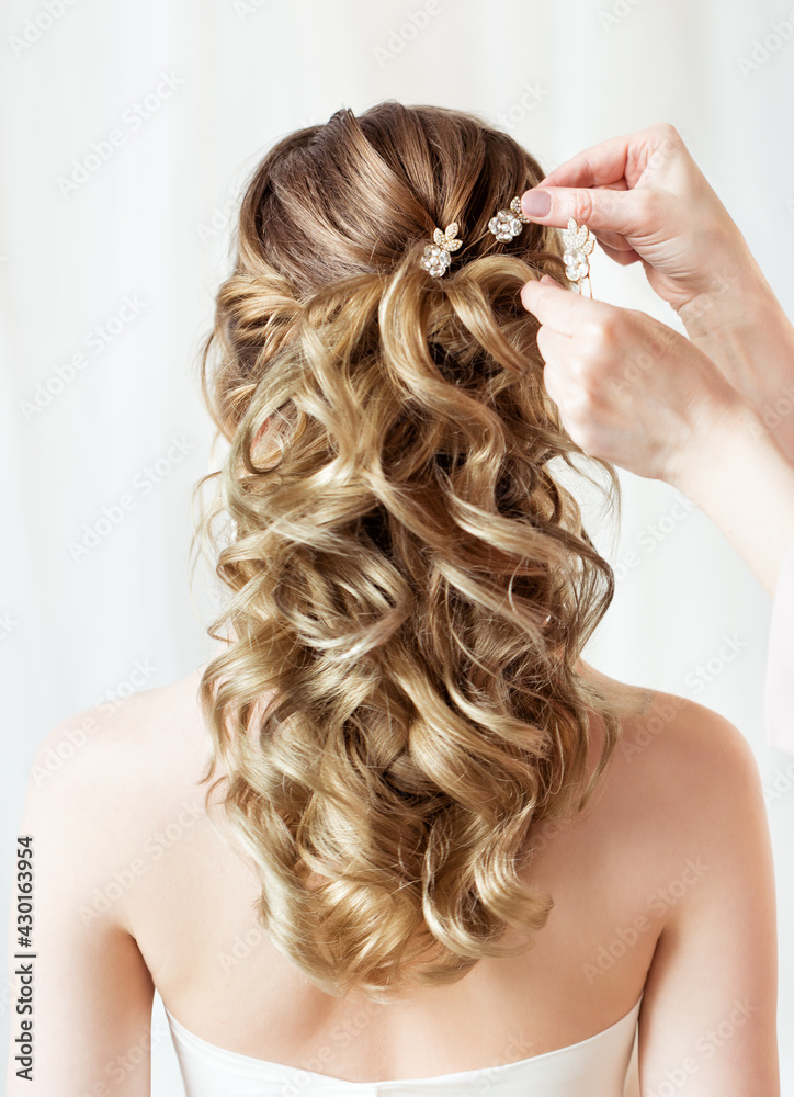 Naklejka premium Wedding Hair Style Back Side View. Bride Hairstyle Accessory Rear View Close up. Hairdresser putting Flower Crystal Hairpin. Wavy curl Evening Hairdo over White Background