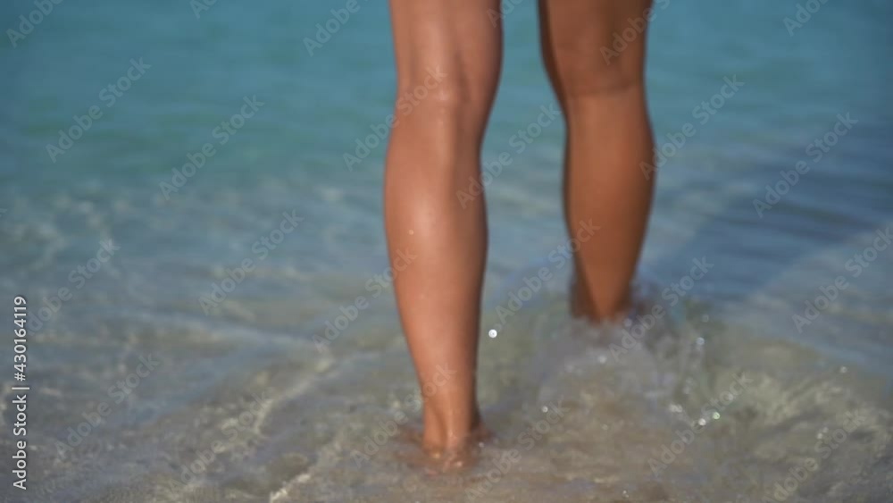 Sexy fit woman in white bikini walking by the beach with crystal water in slow motion. concept of vacation, holiday and resort Sexy fit woman in white bikini walking by the beach with crystal water in slow motion. concept of vacation, holiday and resort