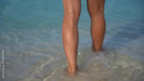 Sexy fit woman in white bikini walking by the beach with crystal water in slow motion. concept of vacation, holiday and resort