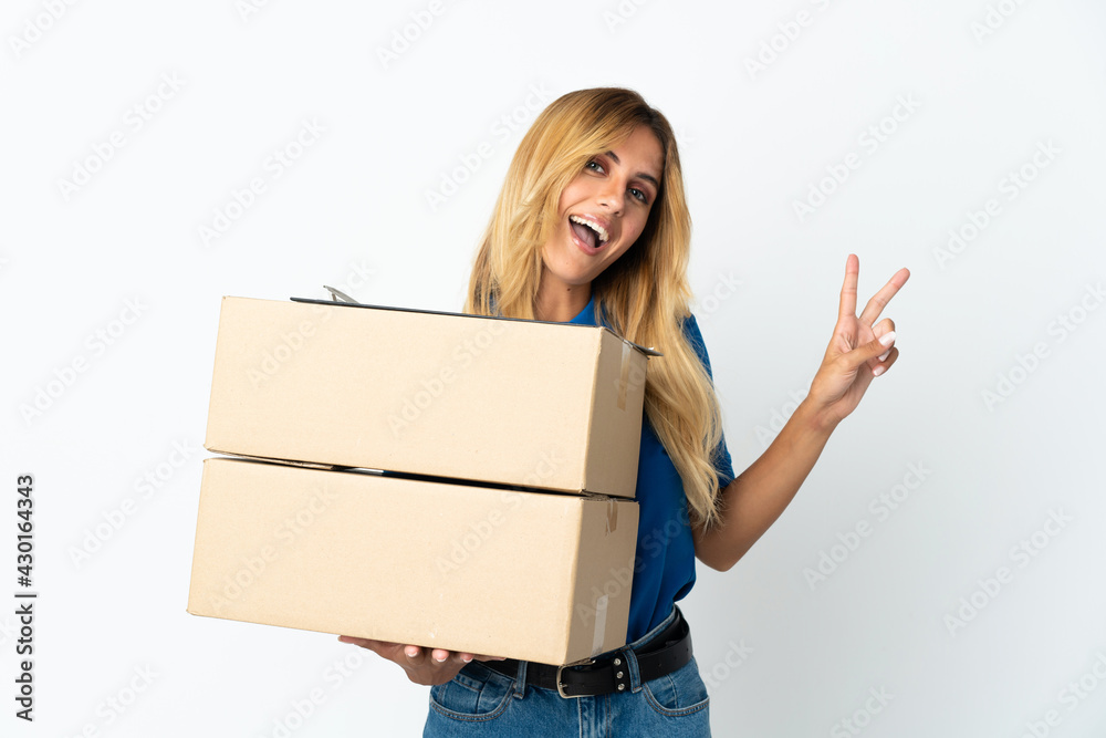 Young blonde Uruguayan delivery woman isolated on white background smiling and showing victory sign Young blonde Uruguayan delivery woman isolated on white background smiling and showing victory sign