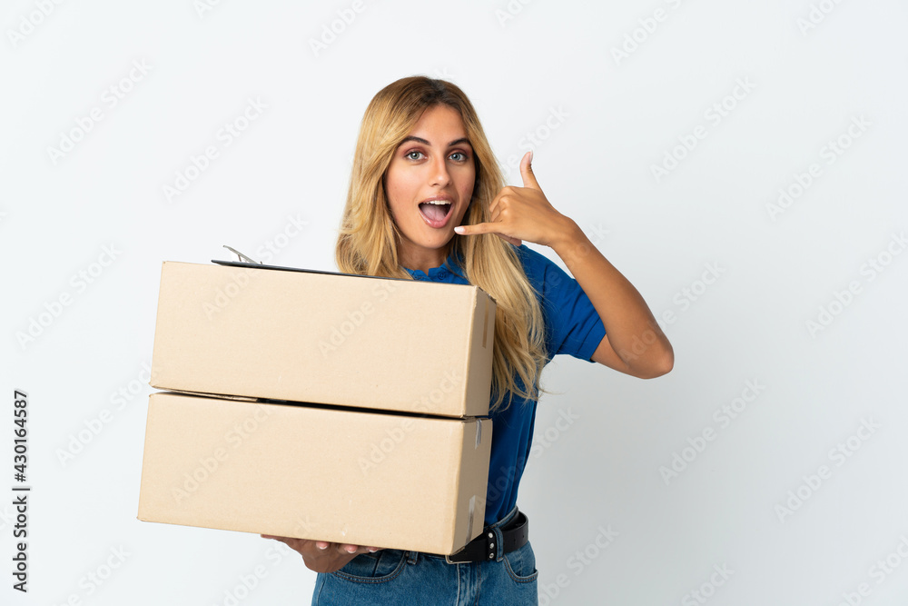 Young blonde Uruguayan delivery woman isolated on white background making phone gesture. Call me back sign Young blonde Uruguayan delivery woman isolated on white background making phone gesture. Call me back sign