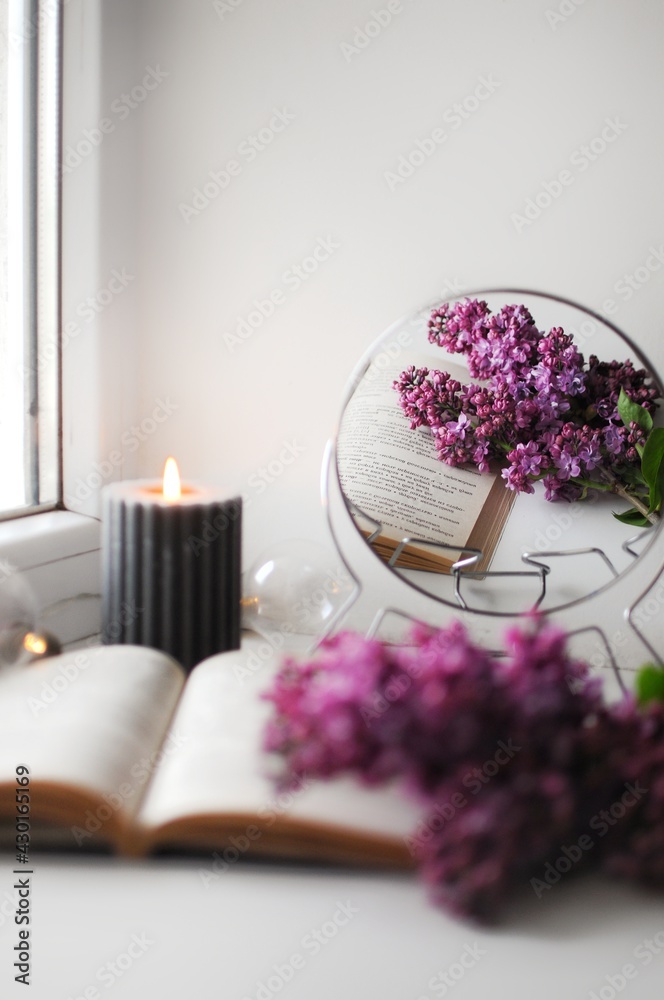 Opened book with a lilac bush. Cozy romantic home atmosphere with a candle.