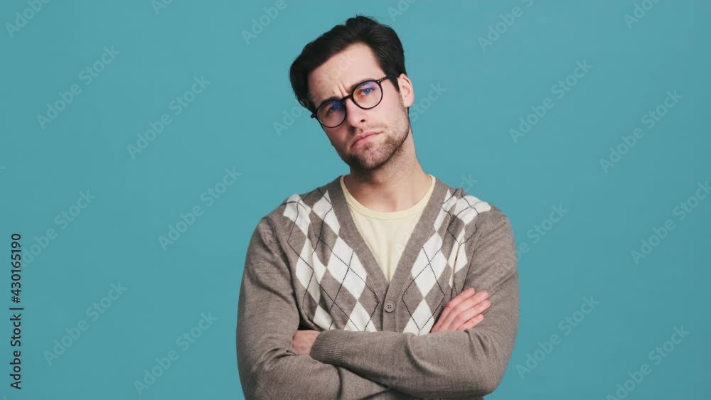A man in glasses with crossing arms in front of him and nodding his head negatively while saying no in a blue studio A man in glasses with crossing arms in front of him and nodding his head negatively while saying no in a blue studio