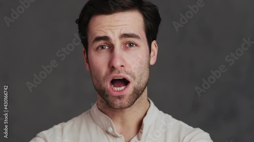 The portrait of a man biting his lip and saying wow while standing in a studio