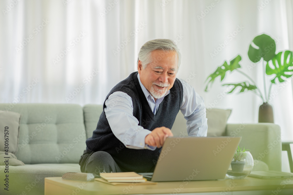 Happiness elderly asian man sitting on sofa and using computer laptop VDO Conference online meeting with family or business team and smile at home,Senior lifestyle at home concept Happiness elderly asian man sitting on sofa and using computer laptop VDO Conference online meeting with family or business team and smile at home,Senior lifestyle at home concept