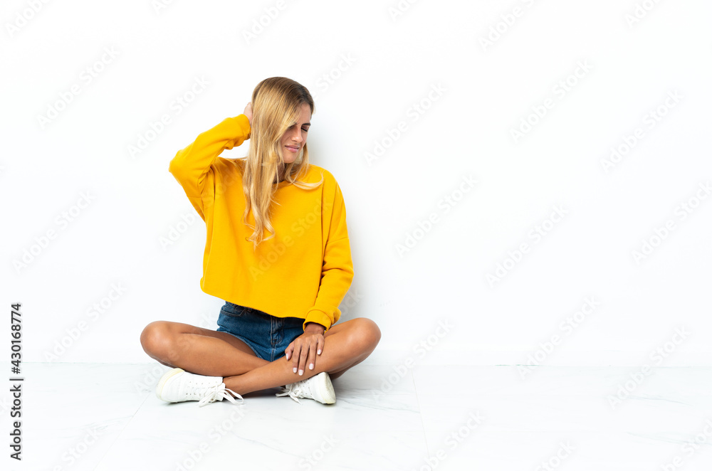 Fototapeta premium Young blonde Uruguayan woman sitting on the floor isolated on white background with neckache